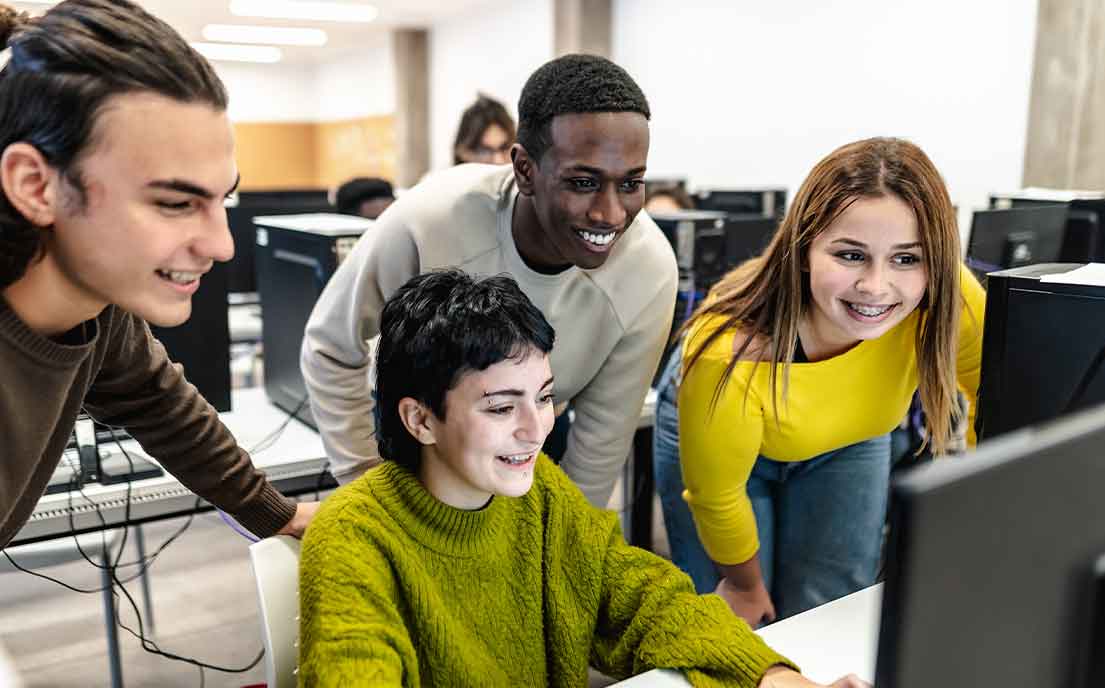 Four students all gathered around a computer.